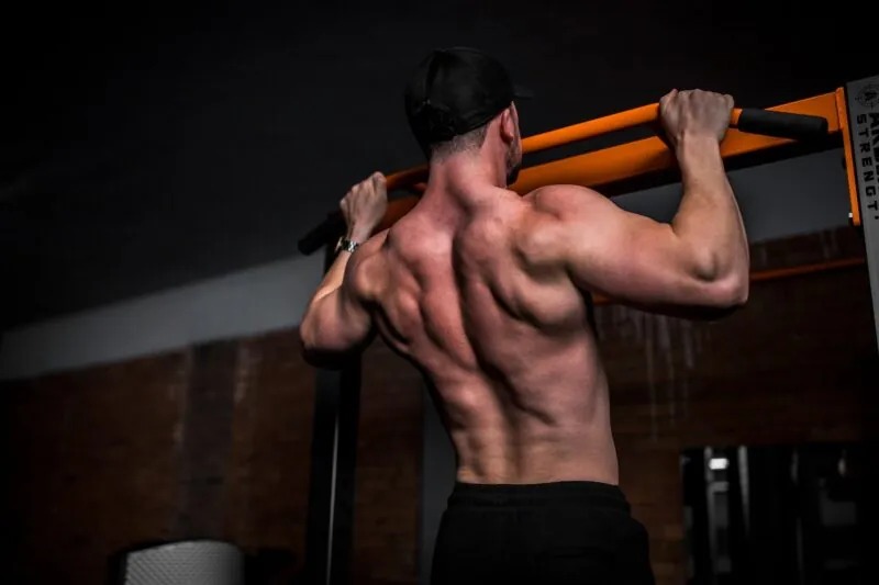 Fit man doing pull ups with nice formed muscles on hid back