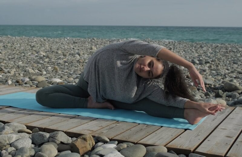 woman starching on the beach - Improve Flexibility