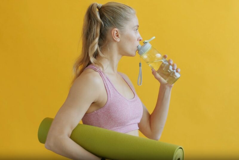 A woman takes a break to hydrate with water as part of her participation in the 30-Day Flexibility Challenge.