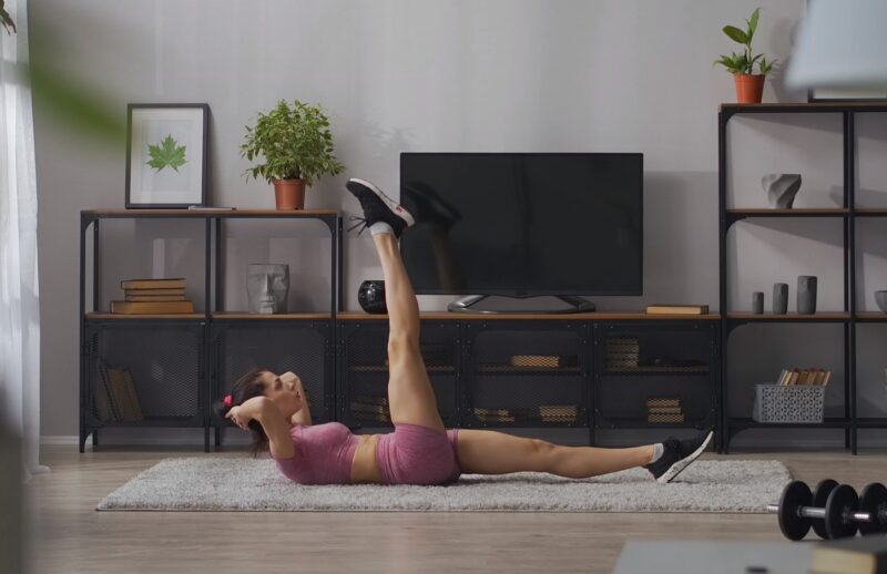 A woman exercising her abdominal muscles in her living room, demonstrating an at-home workout routine.