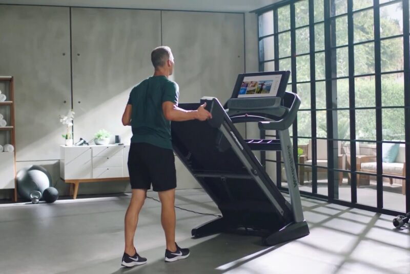 Man assembling a treadmill at home, illustrating the process of selecting the best treadmill for home use.