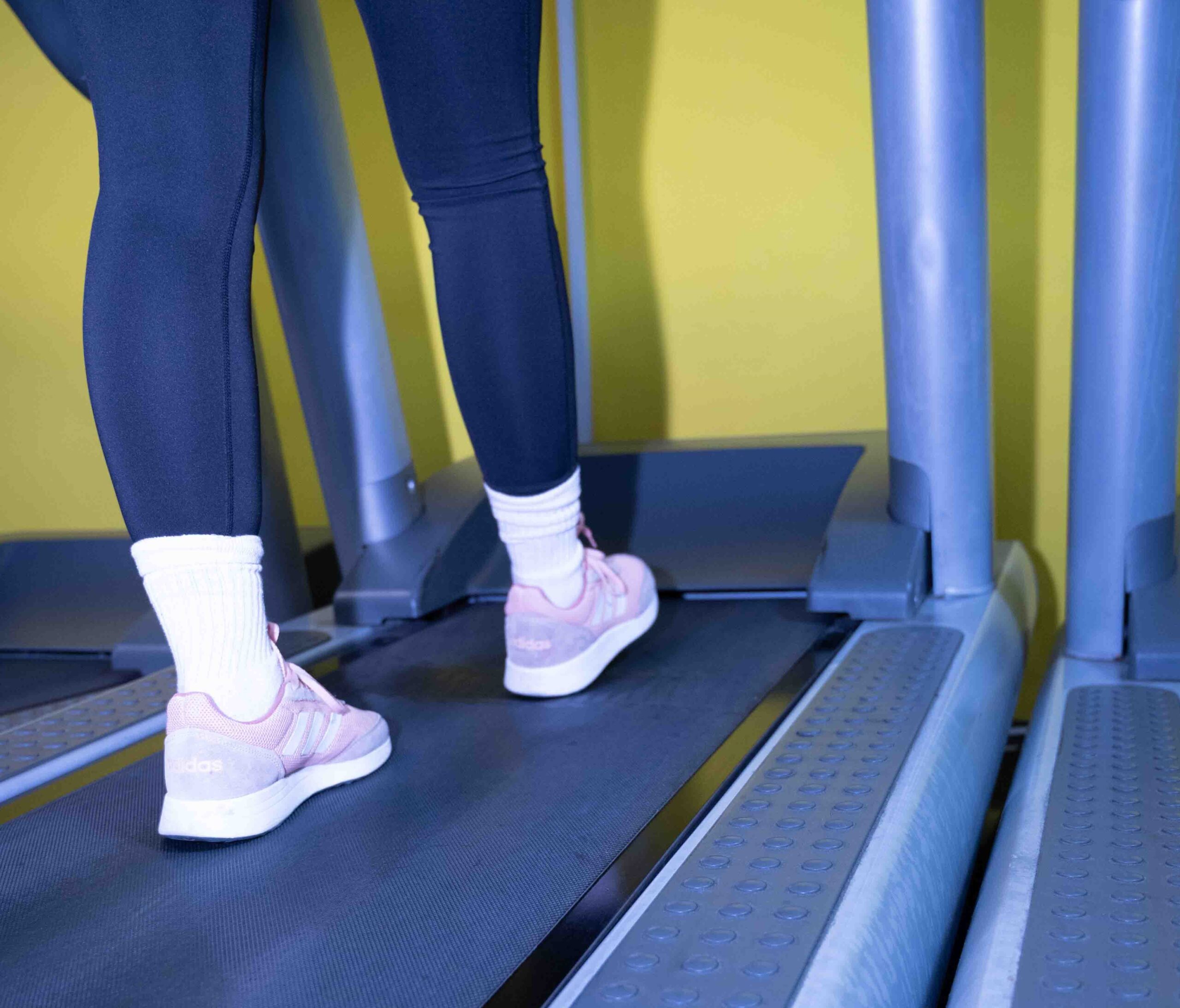 A girl in pink sneakers running on a treadmill